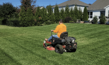 a man on a riding lawn mower mowing a backyard